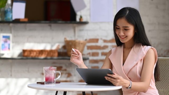 cheerful businesswoman laning work with digital tablet while sitting in cafe